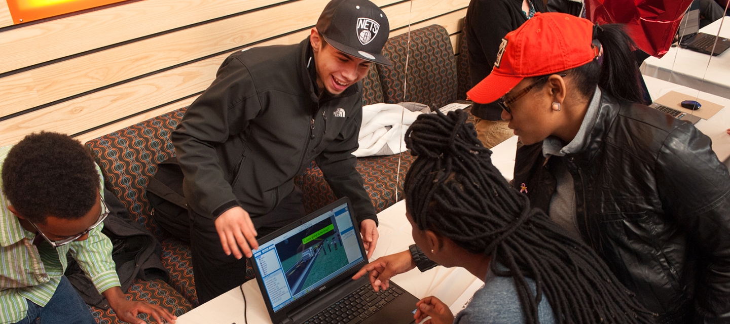 Students pointing to a computer game on a laptop